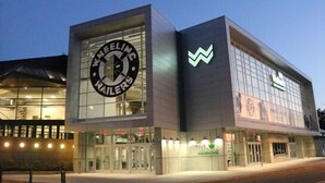 Een modern gebouw met een groot logo op de gevel en een bord waarop ‘WHEELING WARRIORS’ staat.