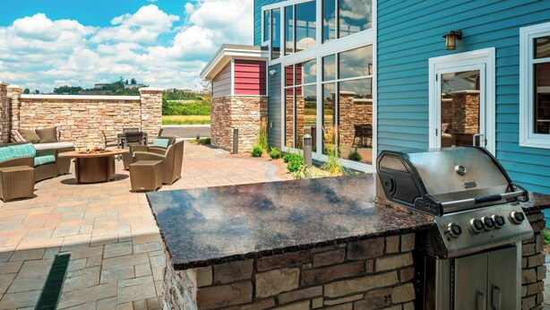 Een terras met stenen muren, een barbecue en tuinmeubilair.