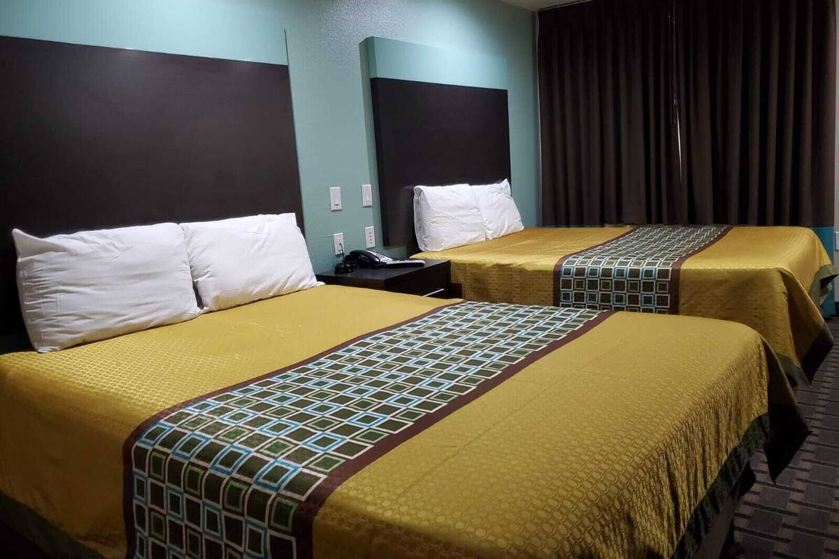 Two single beds with headboards, a telephone, and a window with curtains.