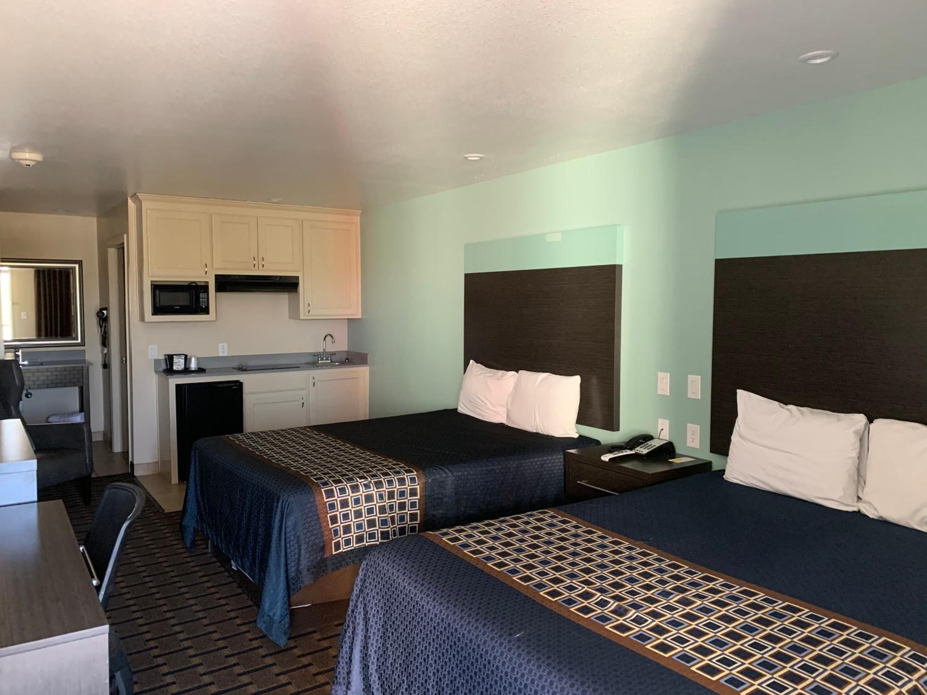 Habitación de hotel con dos camas, kitchenette y baño.