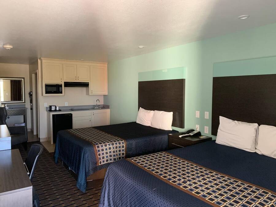 Habitación de hotel con dos camas, kitchenette y baño.