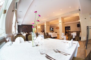 A dining area with tables set for a meal, featuring clear glassware and a vase with flowers. - Hotel Logos (Gdansk)