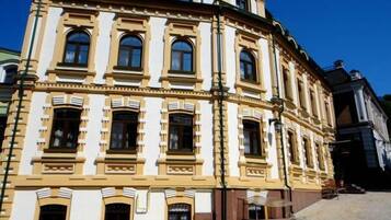 Um edifício histórico com estilo arquitetônico clássico, com várias janelas e uma entrada de esquina imponente.