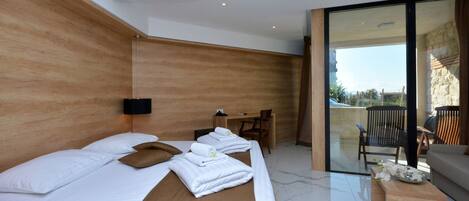 A modern hotel room with a large bed, a desk, and a balcony with a view.