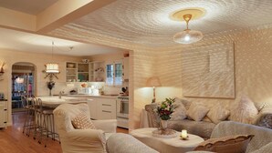 A spacious living area with a sofa, chairs, a coffee table, and a kitchen in the background. -  Auberge Old Chelsea (Chelsea)