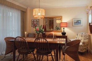 Comedor con una mesa de madera, sillas de mimbre, una vela y un espejo en la pared.
