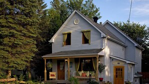 A two-story house with a porch, a front door, and a small garden area. -  Auberge Old Chelsea (Chelsea)