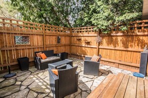 Un patio al aire libre con suelo de piedra, muebles de mimbre y valla de madera.