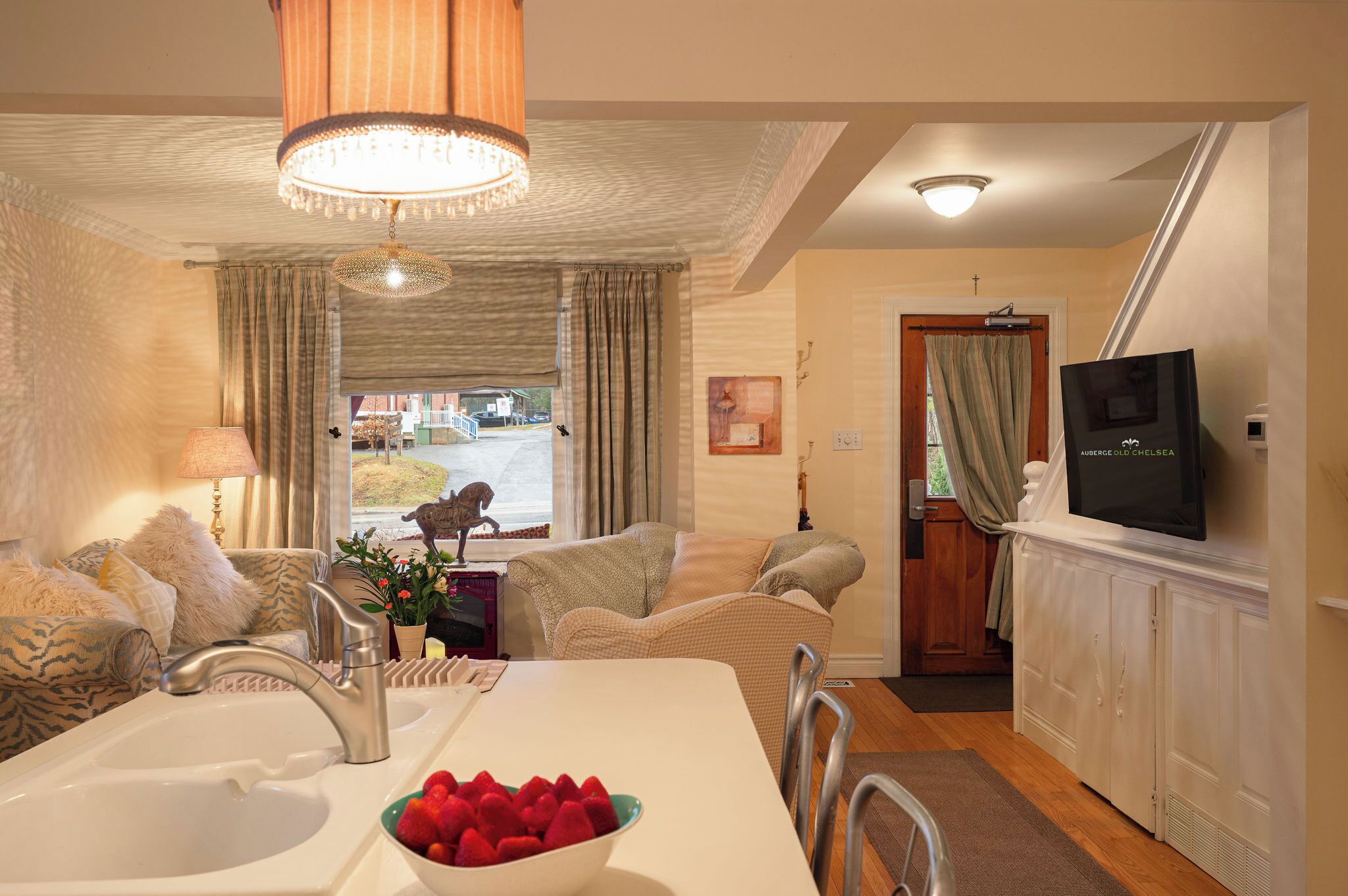 A cozy living room with a dining area, a chandelier, a television, and a view of the outside.