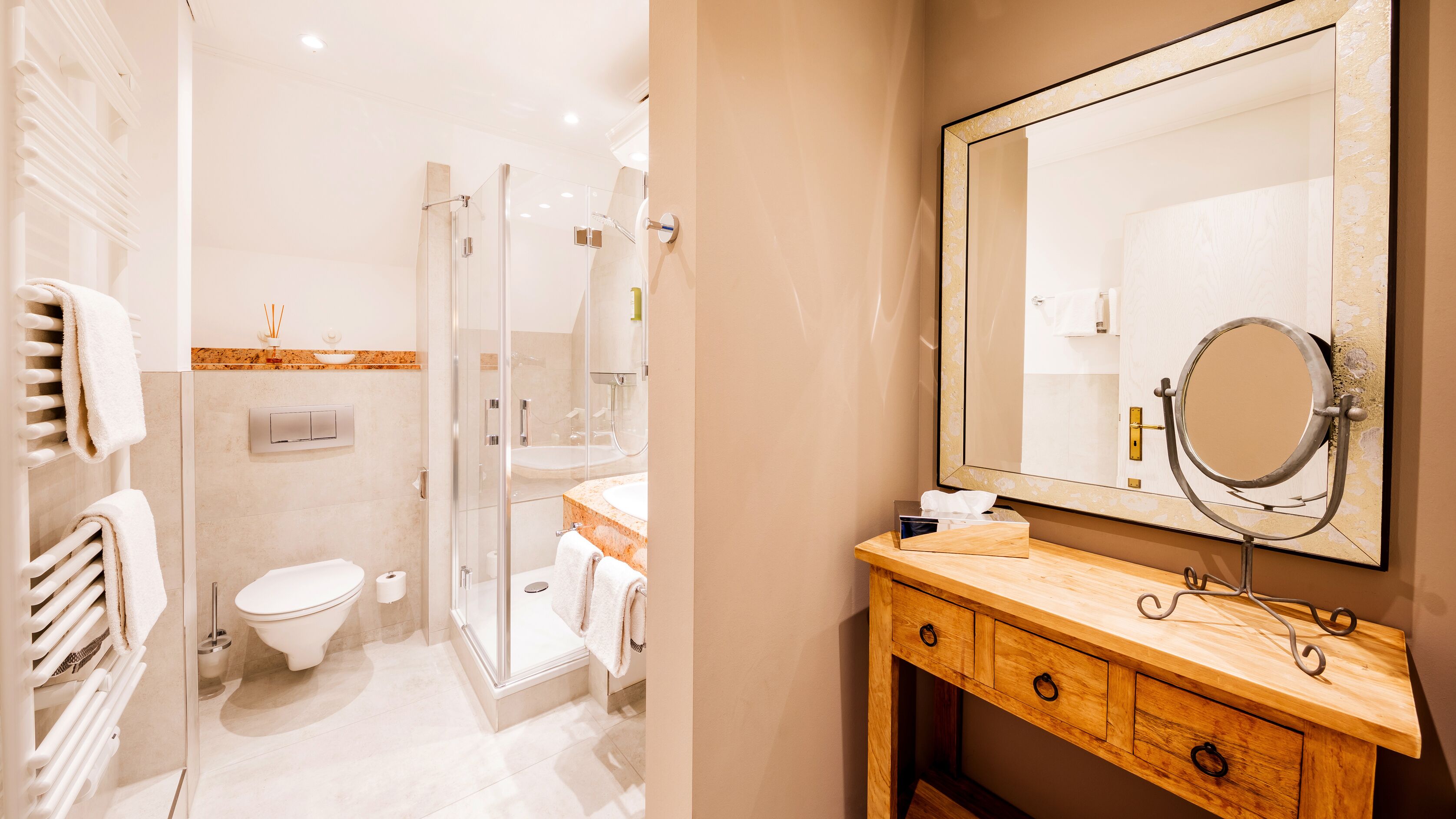 A modern bathroom with a glass shower enclosure, a wooden vanity with a large mirror, and a toilet with a towel rack.