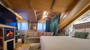 A cozy bedroom with a fireplace, a bed, a sofa, and a view of the outdoors. - Archontariki Boutique Hotel (Ioannina)