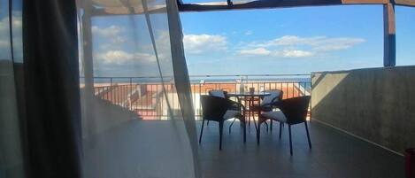 A balcony with a table and chairs, overlooking a cityscape.