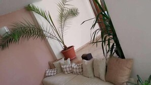 Rincón acogedor con un sofá color beige, cojines estampados y una planta en maceta.