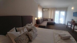 Una habitación de hotel con una cama grande, un sofá, un escritorio y un televisor.