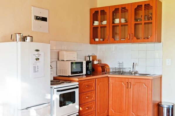Una cocina con armarios de madera, un refrigerador blanco, un microondas, una estufa y un lavamanos.