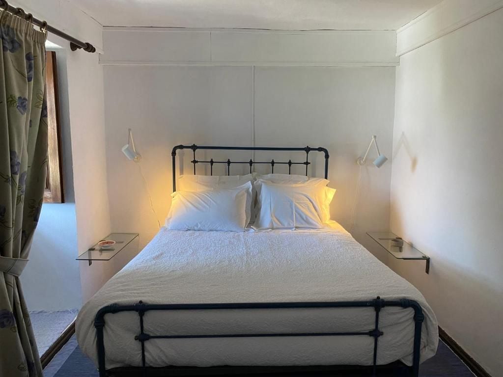 A single bed with a metal frame, white bedding, and two bedside tables with lamps.