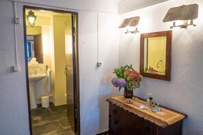 A bathroom with a sink, mirror, and a vase of flowers on a wooden dresser. - Quinta Da Calcada (Melgaço)