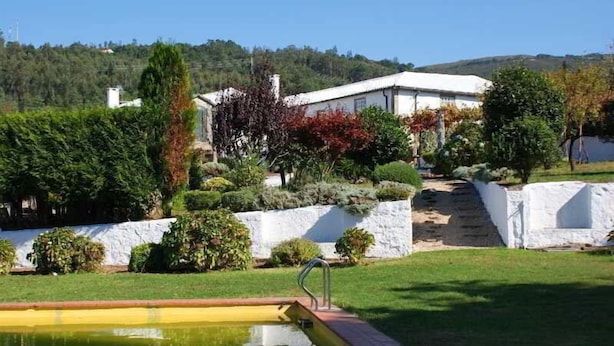 A pool area with a clear view of a white building and surrounding greenery.