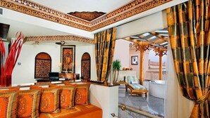 A room with a sofa set, a TV, and a view of an outdoor area with a pool and a pergola. - Pickalbatros Palace Hurghada (Hurghada)