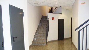 A hallway with a granite floor, a staircase with a handrail, and a door with a handle. - Benicarlo 3000 (Benicarlo)