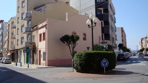 A multi-story building with a flat facade, a small tree in front, and a roundabout with a blue circular sign. - Benicarlo 3000 (Benicarlo)
