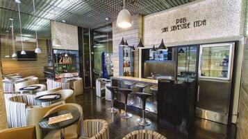Uma área de bar moderna com assentos, balcão e refrigerador.