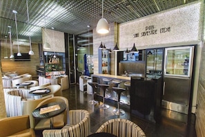 A modern bar area with seating, a counter, and a refrigerator.