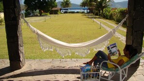 A hammock and a bench overlooking a grassy area with a view of the sea and mountains. - Aquamaster Dive Pousada (Angra dos Reis)