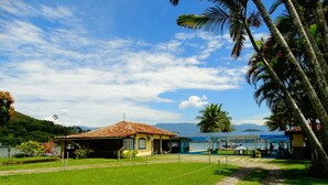 A small, yellow building with a tiled roof, surrounded by a well-maintained lawn and a stone pathway leading to a dock. - Aquamaster Dive Pousada (Angra dos Reis)