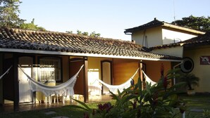 A building with a tiled roof, a porch with hammocks, and a garden area. - Aquamaster Dive Pousada (Angra dos Reis)