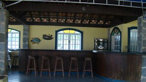 A bar area with wooden stools, a fish mural, and a large window. - Aquamaster Dive Pousada (Angra dos Reis)