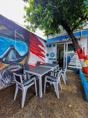 Un espace extérieur aménagé avec des tables, des chaises, un arbre et une fresque murale.