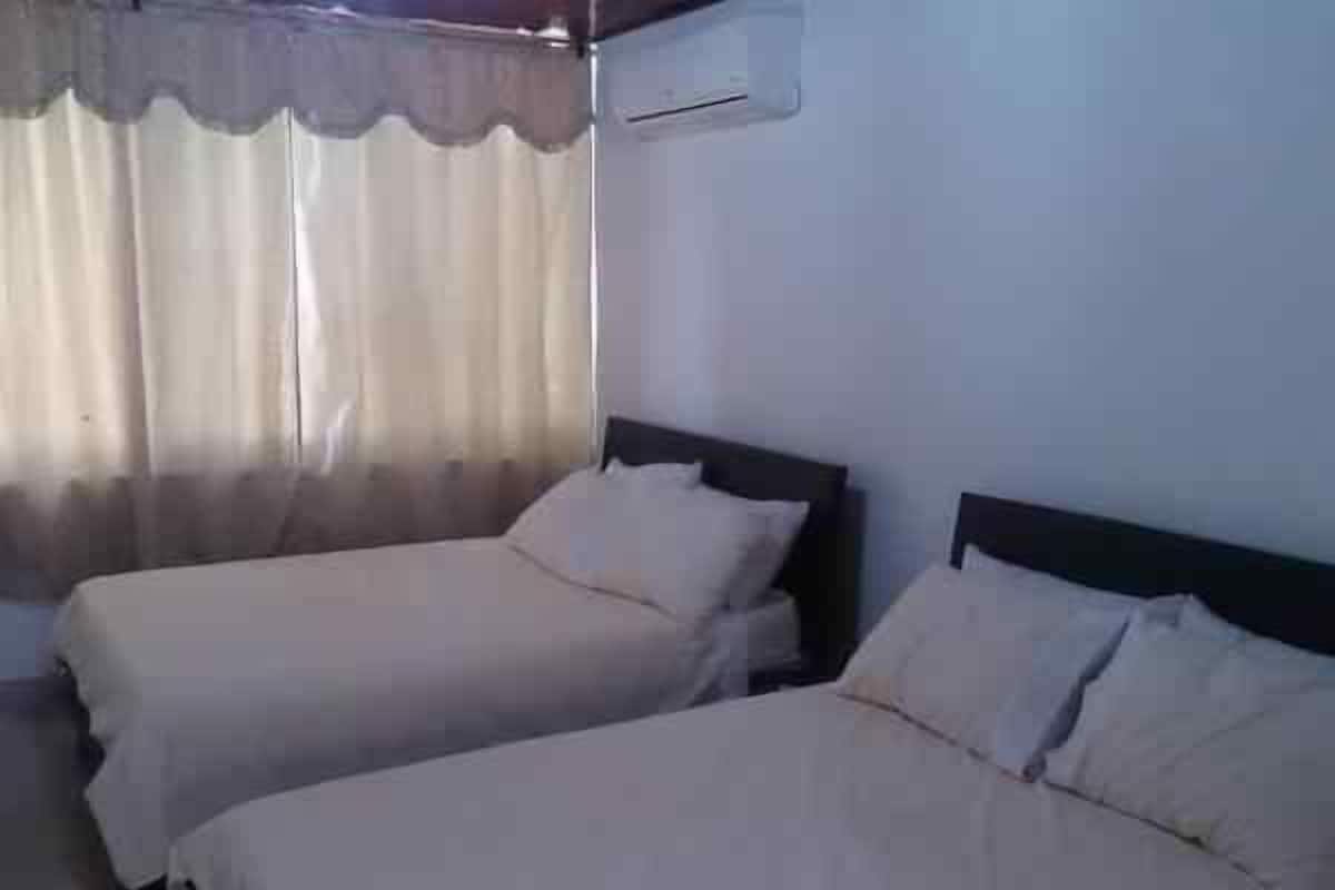 Een kamer met twee bedden, een raam met gordijnen en een airconditioning aan de muur.