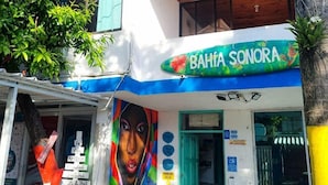 Un bâtiment aux couleurs vives, orné d’une fresque murale, avec une enseigne indiquant « BAHIA SONORA » et des places assises à l’extérieur.