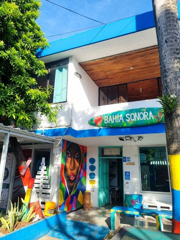 A colorful building with a mural, a sign reading "BAHIA SONORA", and outdoor seating. - Posada Cultural Bahia Sonora (San Andrés)