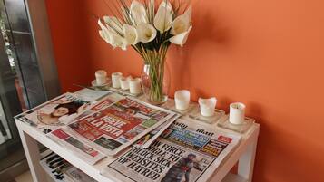 Ett bord med tidningar, en vas med blommor och ljus.