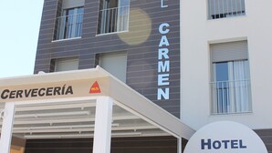 A hotel named Hotel Carmen with a modern facade, a covered outdoor seating area, and a visible entrance. - Hotel Carmen (Mijas)