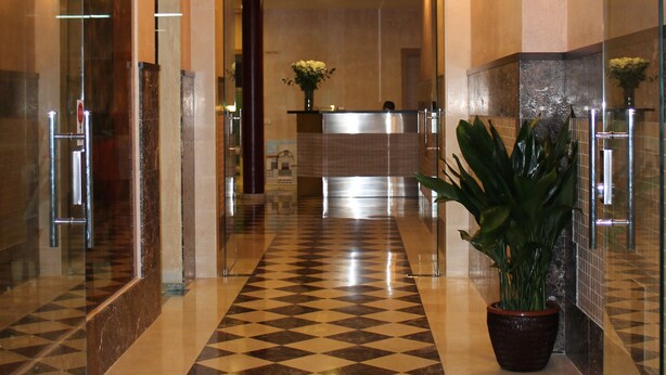 A hotel lobby with a checkered floor, glass walls, and a reception desk in the background. - Hotel Carmen (Mijas)