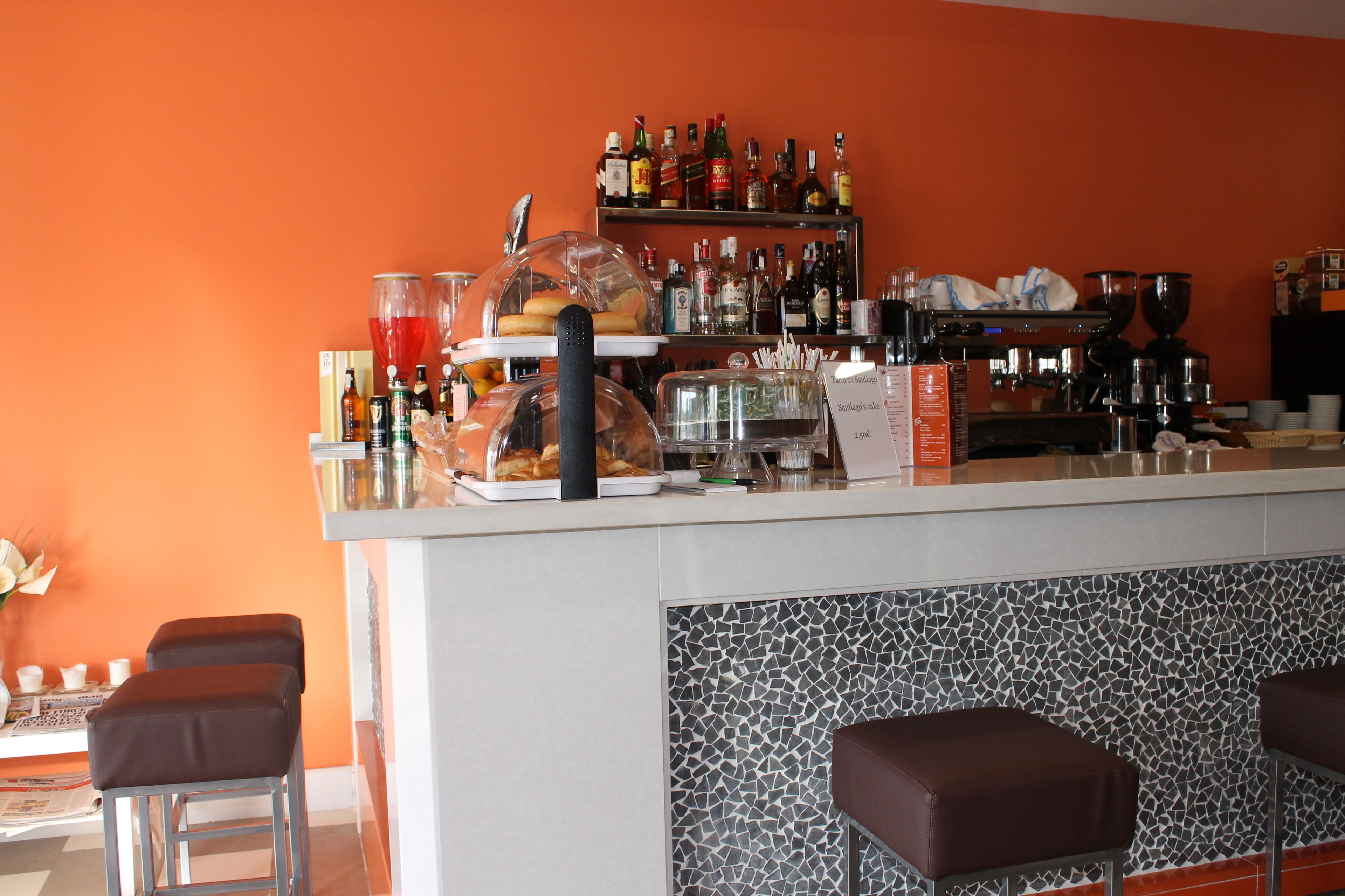A bar area with a counter, stools, and a variety of bottles and glasses.