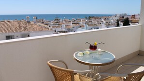 A balcony with a table and chairs, overlooking a coastal town with terracotta rooftops and a clear view of the sea. - Hotel Carmen (Mijas)