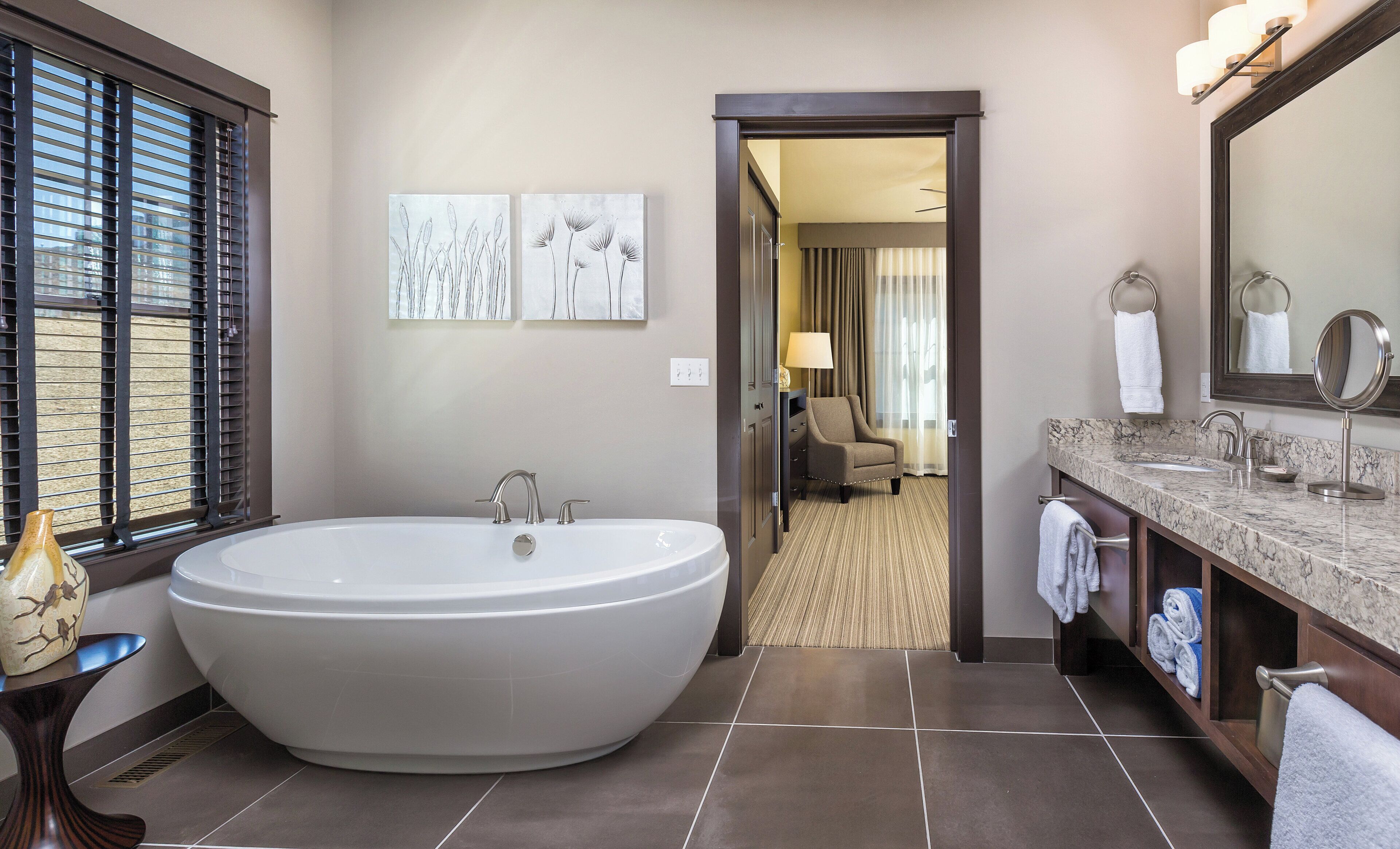 Une salle de bain moderne avec une baignoire sur pieds, un meuble-lavabo en marbre et un grand miroir.