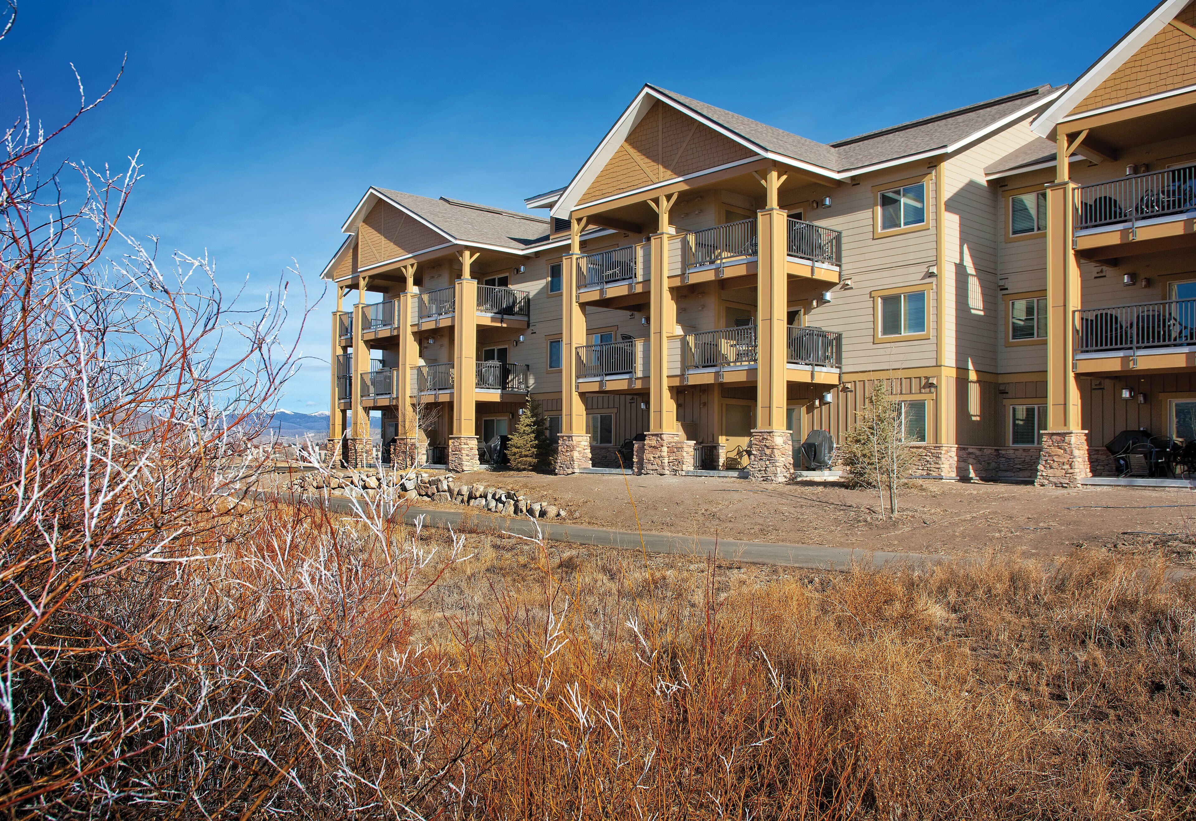 A multi-story hotel with balconies, stone pillars, and a clear sky.