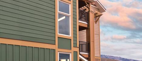 A multi-story building with a green exterior, large windows, and a stone foundation.