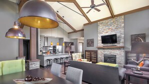 Cozinha moderna com ilha central, banquetas e área de refeições com mesa e cadeiras.