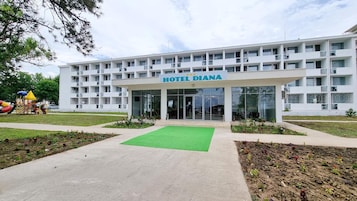 Un hôtel à plusieurs étages, doté d’une façade sobre, d’une pelouse verdoyante à l’avant et d’une aire de jeux sur le côté gauche.