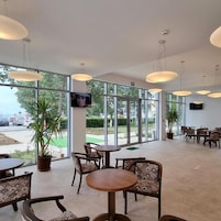 Un espace intérieur vaste et lumineux, doté de grandes fenêtres, de nombreuses tables et chaises, ainsi que de luminaires suspendus.