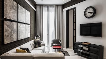 Una sala de estar moderna con un sofá, una mesa de centro, un sillón de cuero negro, un mueble de TV negro y un gran reloj de pared.