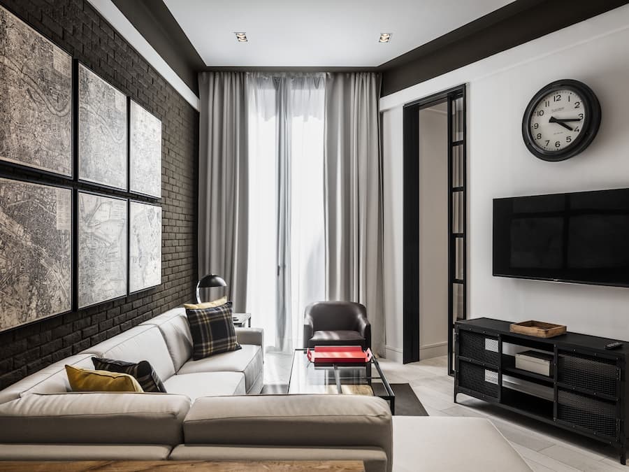 Una sala de estar moderna con un sofá, una mesa de centro, un sillón de cuero negro, un mueble de TV negro y un gran reloj de pared.