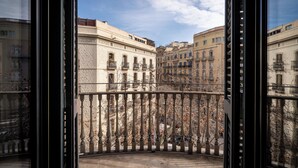 Un balcón con vista a edificios históricos, barandilla de hierro forjado y cielo despejado.