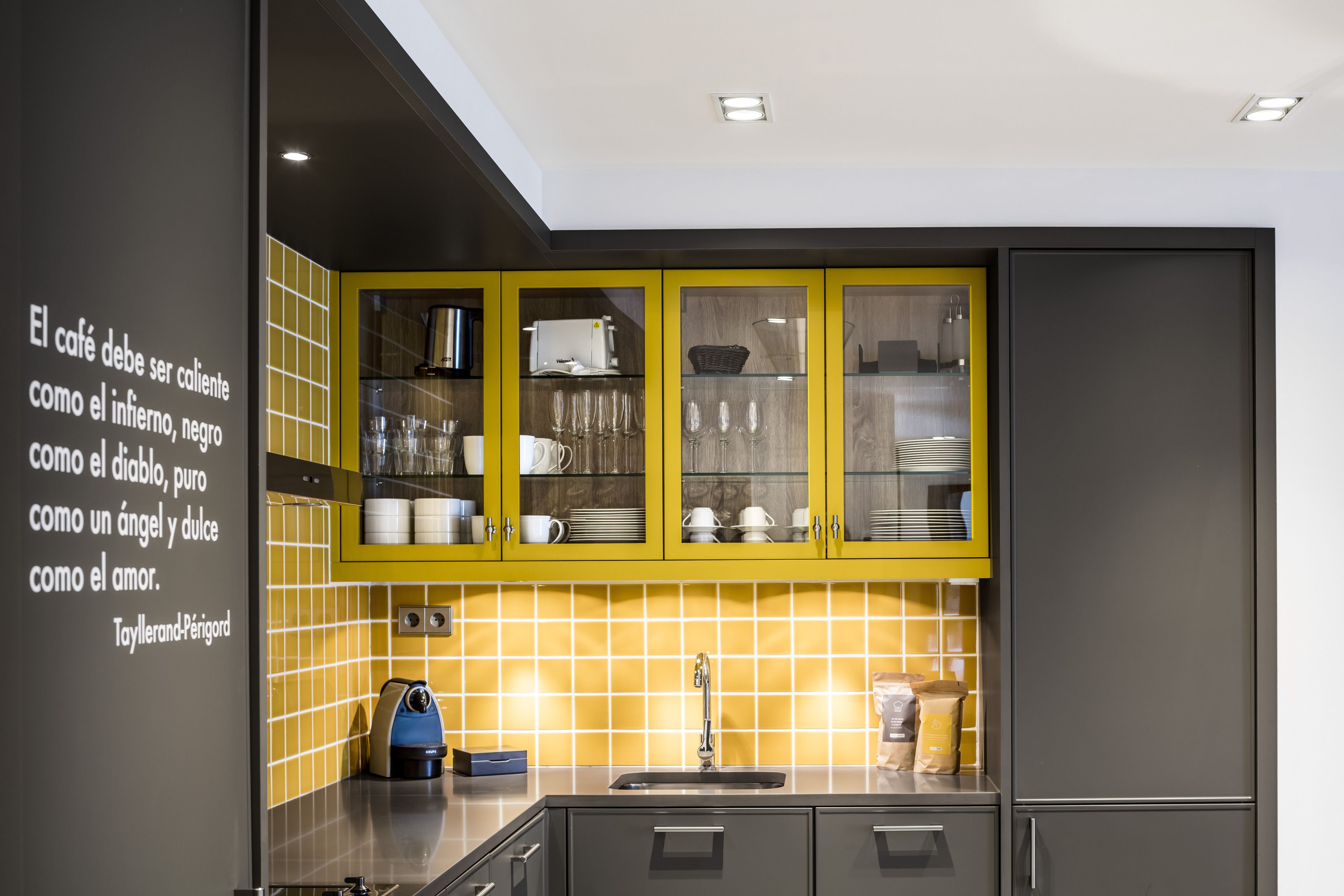A modern kitchen with yellow cabinets, a sink, and a coffee machine.